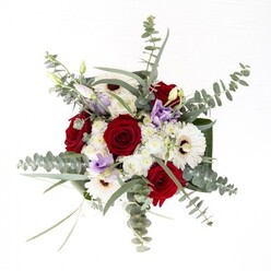 Every element of this bouquet speaks of balance and expertise, a composition that would feel entirely at home in North Ockendon's peaceful residential settings. At the heart are bold, spiraling red roses, their deep hue evocative of enduring affection, bordered by flawless white gerbera daisies with espresso-toned centres. Wisps of silvery eucalyptus rise above, adding sculptural interest and aromatic nuance that recalls the comforting green spaces near Fen Lane. Between these mainstays, gentle lilac lisianthus-some blooming, others poised-inject a delicate, modern charm. Diminutive white filler flowers lend body and airiness, their clusters reminiscent of early springtime you might spot along Brandon Groves paths. The glass vase reveals bright, healthy stems, testament to the bouquet's freshness, while broad, dark leaves enfold the base, creating a sense of cohesion and artistry. This deeply inviting arrangement brings together form, fragrance, and the warmth of neighbourly care, providing an ideal gesture for anniversaries, welcoming new neighbours, or simply adorning a light-filled North Ockendon home with seasonal grace.