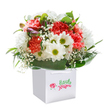 With a playful embrace of color and texture, this North Ockendon bouquet delivers pure joy and heartfelt sentiment, all within a crisp white gift bag poised for local delivery. Soft coral and vibrant red carnations take center stage, their ruffled petals inviting touch and admiration, while snowy white daisies-each sporting a cheery yellow-green eye-bring a sense of innocence and optimism, like a burst of spring near Ockendon's village green. Baby's breath dances lightly among the blooms, its tiny white flowers offering a cloud-like softness, and touches of purple-tinged buds peep out from the foliage, hinting at hidden wonders yet to unfold. Surrounding this lively bouquet, glossy, deep green leaves arc outward in a lush frame, grounding the arrangement in natural elegance. The sturdy white bag, topped with neat ribbon handles, promises an effortless gifting experience-whether celebrating a birthday, welcoming a new neighbour, or simply sending a spontaneous smile across North Ockendon. Lit perfectly against a clean white backdrop, every petal and leaf is showcased with loving precision, revealing the artistry, care, and local pride that define Floral Delivery North Ockendon's creations.